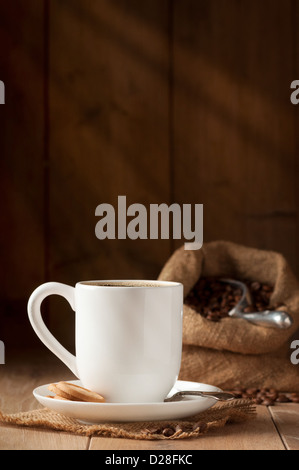 Tasse de café avec des biscuits sur le tapis de jute avec café en grains en arrière-plan Banque D'Images