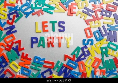 "Let's Party' - aimants pour réfrigérateur messages sort sur un fouillis de lettres Banque D'Images