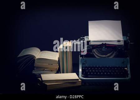 Vieille machine à écrire avec des livres ouverts, des couleurs rétro sur fond noir Banque D'Images