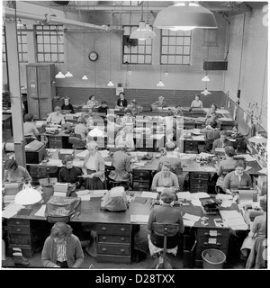 Années 1950, Historique. Pool de typage dans une usine. Le personnel de secrétariat féminin est assis à de grands bureaux au travail dans un espace ouvert et haut plafond d'un bâtiment d'usine. Banque D'Images