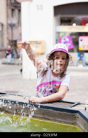 Fille jouant avec de l'eau de fontaine. Banque D'Images