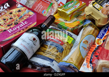 Aliments achetés dans un supermarché : pizzas, vigne, pâtes, beurre, sucre, oeufs. Banque D'Images