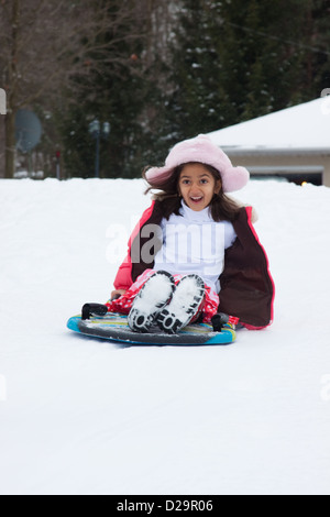 Une bonne fille indienne orientale descend une pente sur un toboggan Banque D'Images