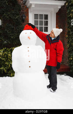 Une fille asiatique la construction d'un vrai bonhomme de neige à l'extérieur dans un jardin Banque D'Images