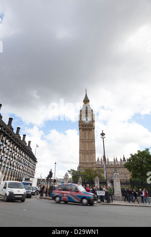 Un London cab avec un dessin du drapeau de l'Union entre la Place du Parlement avec les autres types de trafic avec Big Ben en arrière-plan. Banque D'Images