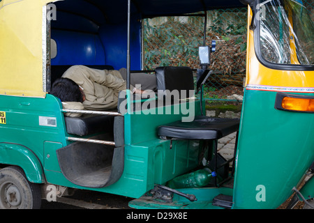 Un auto rickshaw driver dort dans sa cabine à Bangalore, Inde Banque D'Images