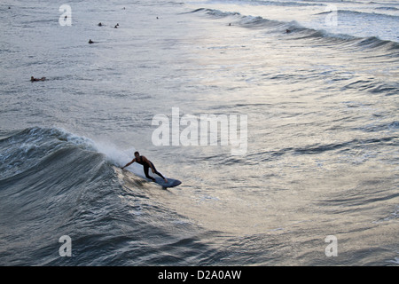 Un surfer une vague de l'ouragan sandy's à Folly Beach, Caroline du Sud alors que d'autres surfeurs. Banque D'Images