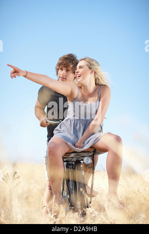 Couple riding bicycle in tall grass Banque D'Images