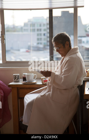 Femme avec Ipad / Tablet à fenêtre de cuisine à Mexico DF Banque D'Images