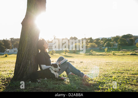 Woman relaxing with dog in park Banque D'Images