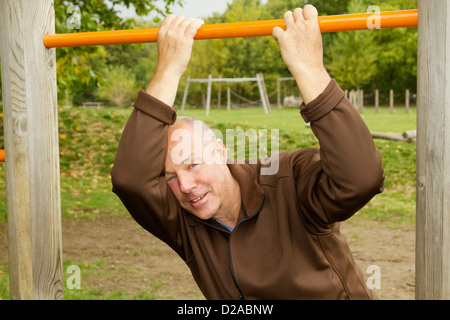 Homme plus âgé pendaison de jungle gym Banque D'Images