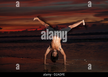 Jeune homme faisant la capoeira sur la plage au coucher du soleil Banque D'Images