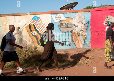 Deux femmes du nord de l'Ouganda et d'une lycéenne devant un mur peint avec une peinture murale montrant une carte de l'Afrique au début du matin Banque D'Images