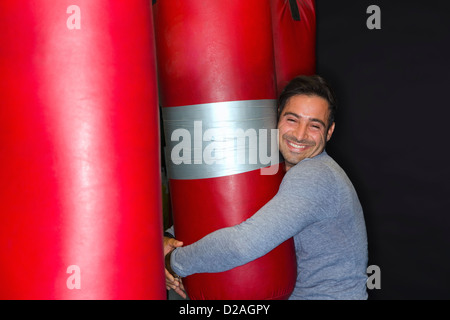 Smiling boxer hugging punching bag Banque D'Images