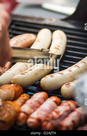 Close up de saucisses cuisson sur grill Banque D'Images