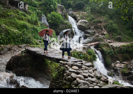 Deux filles de l'école font leur chemin à la maison après l'école le long d'une route de montagne dans le district de Dolakha. Banque D'Images