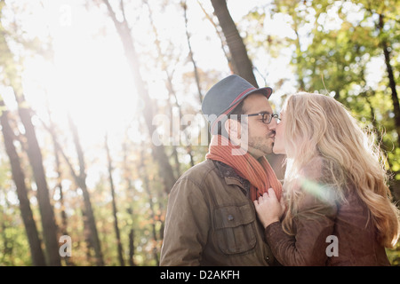 Smiling couple kissing in forest Banque D'Images