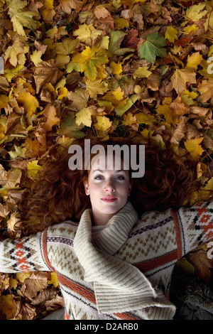 Woman laying in autumn leaves Banque D'Images