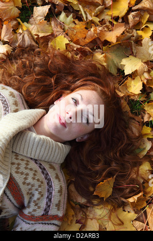 Woman laying in autumn leaves Banque D'Images