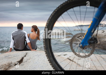 Couple relaxing on boulder par ocean Banque D'Images