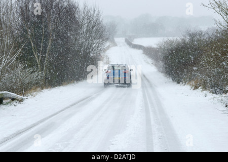 Une voiture se déplace le long d'une route couverte de neige dans la région de Chester UK Banque D'Images