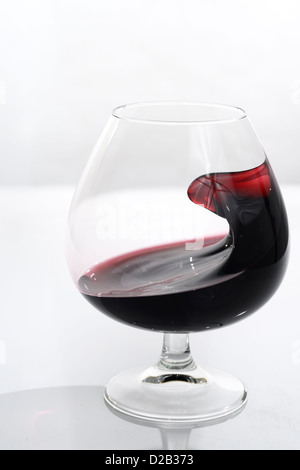 Forme étrange de port en agitant un petit verre en verre sur fond blanc Banque D'Images