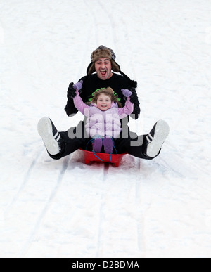 Le père et sa fille s'amusant de la luge sur la neige fraîche Banque D'Images