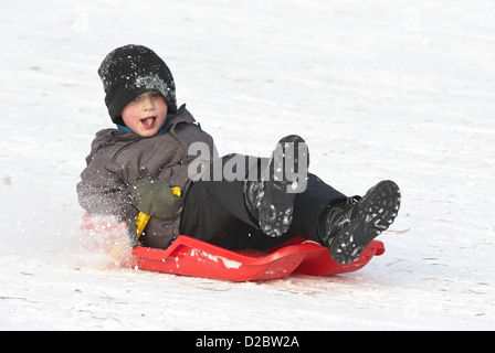 Enfant Garçon (6-8) sur un traîneau bob, neige, hiver Banque D'Images