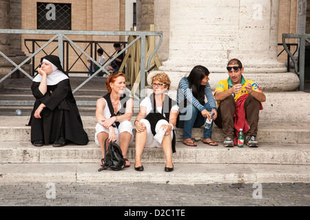 Les touristes et une religieuse assise dans la place Saint Pierre, le Vatican, Rome Banque D'Images