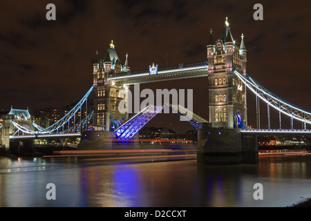 Il s'agit d'une image de Tower Bridge ouvert pour passer à travers le trafic nautique, vous pouvez voir les sentiers de la lumière d'un bateau qui passe. Banque D'Images