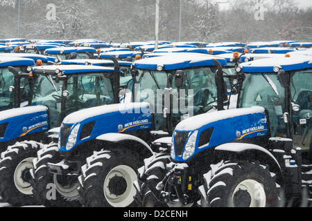 Rangées de couverts de neige, les nouveaux tracteurs de marque, alignés, prêts pour la livraison de l'usine de tracteurs New Holland de Basildon, Essex. Banque D'Images