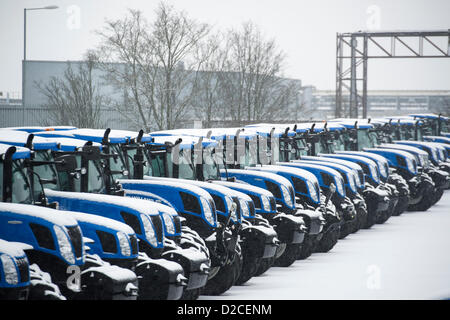 Rangées de couverts de neige, les nouveaux tracteurs de marque, alignés, prêts pour la livraison de l'usine de tracteurs New Holland de Basildon, Essex. Banque D'Images