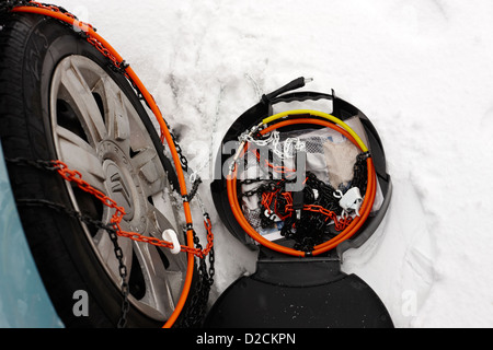 Le montage des chaînes à neige sur un véhicule roue dans la neige profonde en hiver newtownabbey uk Banque D'Images