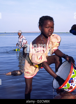 Une jeune fille du groupe ethnique Peul du Mali, Afrique de l'Ouest, aide sa mère nettoyer la vaisselle dans le fleuve Niger. Banque D'Images