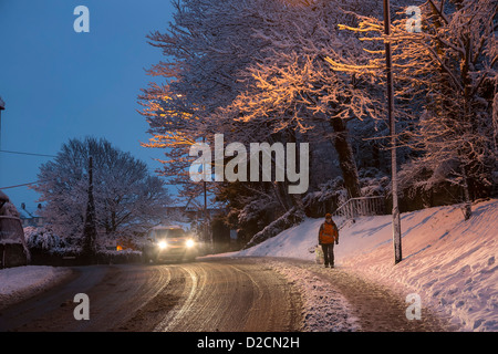 Femme marche sur chaussée glissante en hiver avec voiture passé, Galles, Royaume-Uni Banque D'Images