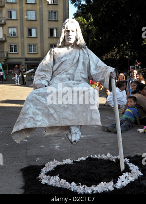 Artiste de rue mime pénitent dans un sac et cendres plane en lévitation apparente au-dessus d'une guirlande de fleurs à Oaxaca zocalo Banque D'Images