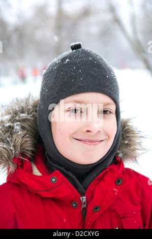 Smiling boy wearing red jacket dans snow park Banque D'Images