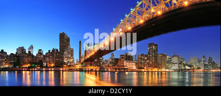 Queensboro Bridge over New York City East River au coucher du soleil avec des reflets de la rivière et de midtown Manhattan illuminé. Banque D'Images