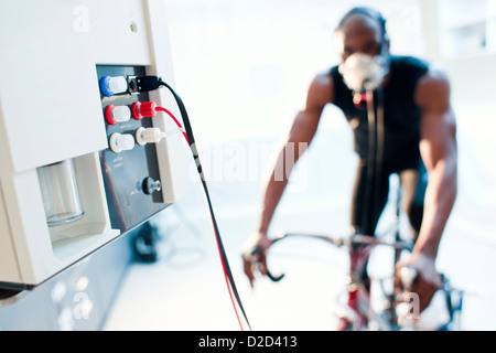 Les tests de performances de parution du modèle sportif équitation un vélo d'exercice alors que son rendement et la consommation d'oxygène sont mesurées Banque D'Images