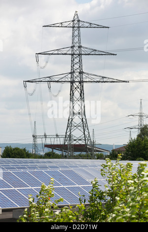 Panneaux solaires en face d'un pylône d'électricité Banque D'Images