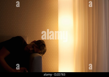 L'homme allongé sur la table à côté de la lumière électrique rougeoyante Banque D'Images