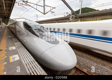 Iwakuni, Japon - 3 mai 2012 : UNE vitesse des trains Shinkansen passé un train à l'arrêt à la gare Shin-Iwakuni Banque D'Images