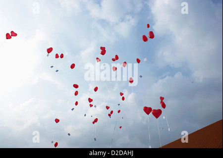 De nombreux ballons à l'hélium en forme de coeur rouge flottant Banque D'Images