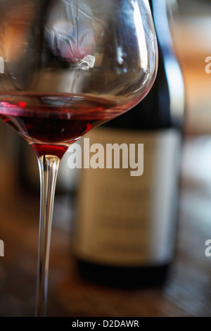 Un verre de vin rouge et deux bouteilles de vin en arrière-plan Banque D'Images