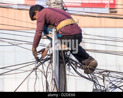 Un électricien travaille sur un enchevêtrement de fils électriques à Katmandou, au Népal. Banque D'Images