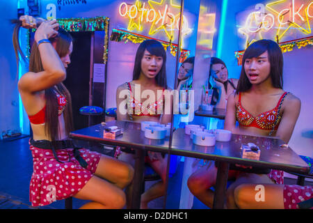 12 janvier 2013 - Bangkok, Thaïlande - Ladyboy (transsexuels) amuseurs vérifier eux-mêmes dans le miroir en face de la barre dans le cacatoès soi Cowboy red light district à Bangkok. En Thaï, les ladyboys sont appelés kathoey. De nombreux travaux dans le divertissement et vie nocturne des secteurs de l'économie thaïlandaise. La prostitution en Thaïlande est illégal, même si dans la pratique, il est toléré et en partie réglé. La prostitution est pratiquée ouvertement dans tout le pays. Le nombre de prostituées est difficile à déterminer, les estimations varient considérablement. Depuis la guerre du Vietnam, la Thaïlande a acquis une notoriété internationale parmi Banque D'Images