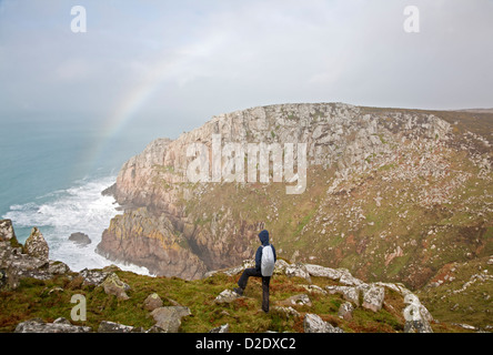 Walker par temps humide admire un arc-en-ciel sur la mer Bosigran falaise près de Cornwall UK Zennor Banque D'Images