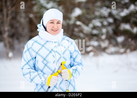 Jeune femme russe debout avec des bâtons de ski dans une profonde forêt d'hiver Banque D'Images