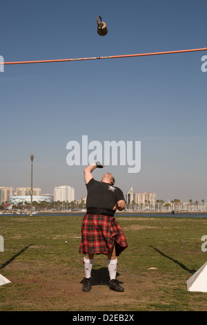 Un homme en kilt rouge lance un poids au-dessus de la barre à l'Scotsfest Queen Mary à Long Beach, CA Banque D'Images