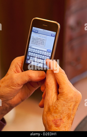Femme âgée, un message SMS sur un iphone à puce Banque D'Images